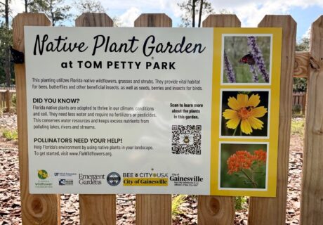 Sign about the Native Plant Garden at Tom Petty Park, describing its role in supporting pollinators, with plant photos, logos, and a QR code for more information.